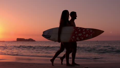 Cute-couple-walking-on-the-beach-with-surfboard