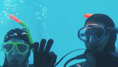 Couple-in-scuba-diving-making-ok-sign-with-hands