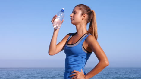 Fit-woman-drinking-water-on-the-beach