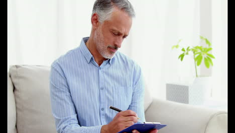 Portrait-of-a-smiling-doctor-writing-notes-on-his-clipboard