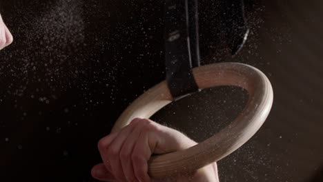 Slow-motion-close-up-shot-of-caucasian-hands-gripping-wooden-gymnastic-rings