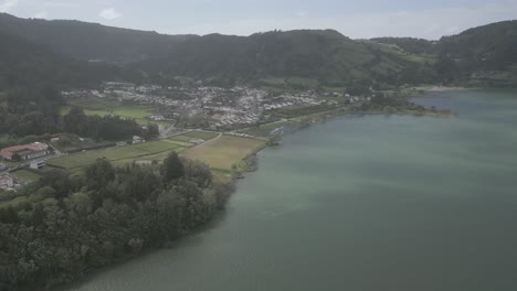 Sete-cidades-village-by-the-lake-with-lush-green-hills-and-serene-water,-aerial-view