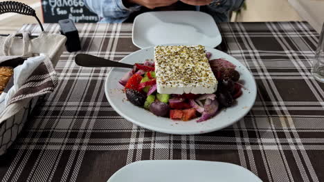 Woman-with-her-phone-in-her-hand-taking-a-picture-of-a-greek-salad-with-Feta-on-a-tavern