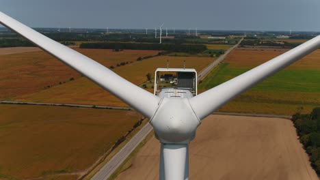 Windturbine,-Nahaufnahme-Der-Nasenkegel-Und-Propeller-Mit-Ackerland-Im-Hintergrund,-Luftaufnahme-Einer-Drohne