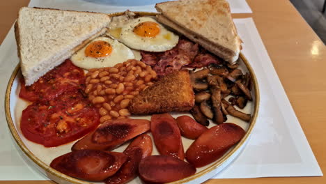 Traditional-English-Breakfast---plate-with-fried-eggs,-sausages,-beans,-mushrooms-and-bacon