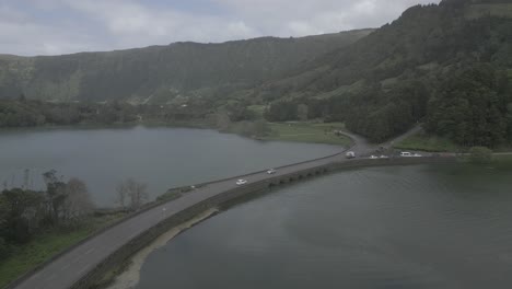 Eine-Brücke-über-Einen-Ruhigen-See,-Umgeben-Von-üppigen-Grünen-Bergen-In-Sete-Cidades,-Luftaufnahme
