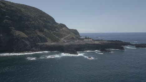 Ponta-da-ferraria-on-a-sunny-day-with-waves-crashing-against-the-rocky-shore,-aerial-view