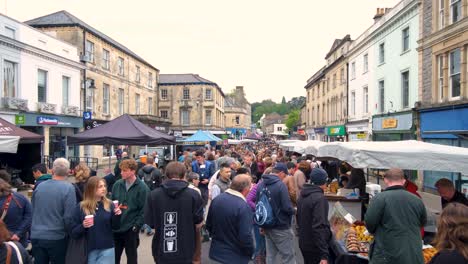 Crowds-of-people-visiting-and-shopping-the-popular-Frome-Farmers-Market-with-stalls-of-arts,-crafts,-food-and-drink-on-the-high-street-in-Somerset,-England