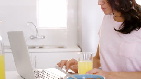 Woman-having-her-breakfast-and-using-her-laptop