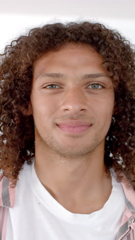 Vertical-video:-A-young-biracial-man-with-curly-hair-and-blue-eyes-is-pictured