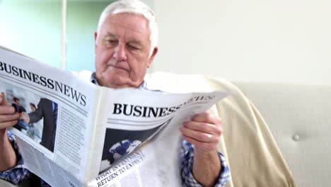 Senior-man-reading-newspaper-on-couch