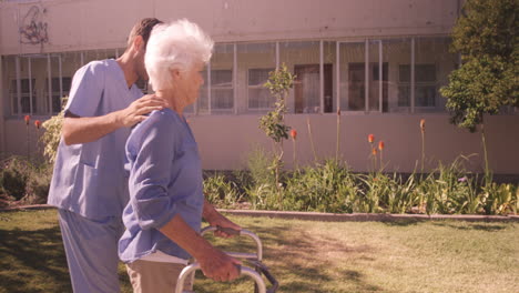 Enfermero-Ayudando-A-Una-Mujer-Mayor-A-Caminar-En-El-Jardín