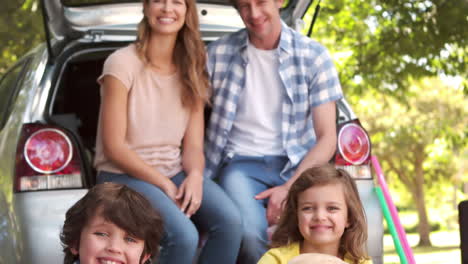 Family-with-dog-sitting-in-car-trunk