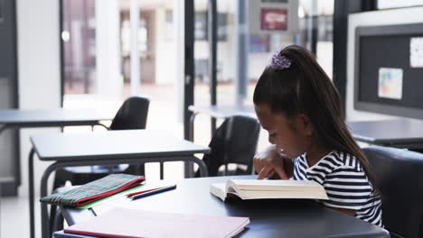 In-a-school-classroom,-a-young-African-American-girl-is-focused-on-reading-with-copy-space