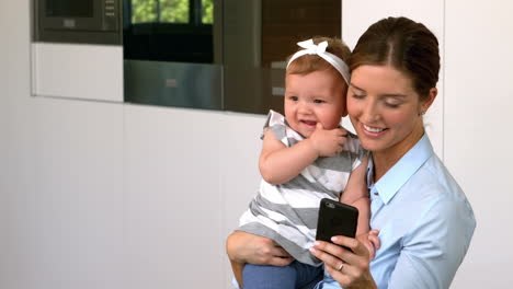 Mother-holding-daughter-and-using-phone