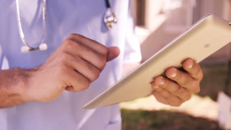 Primer-Plano-De-Un-Médico-Varón-Usando-Una-Tableta-Digital-En-El-Patio-Trasero