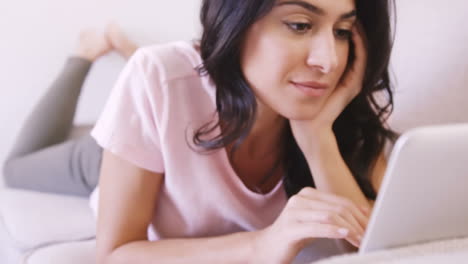 Woman-lying-on-a-sofa-using-her-laptop