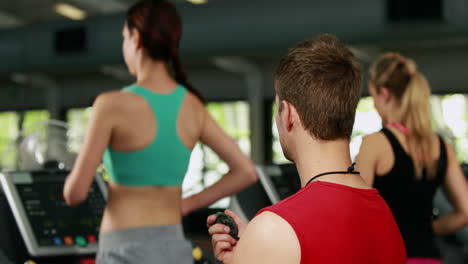 Entrenador-Masculino-Comprobando-El-Rendimiento-De-La-Cinta-De-Correr