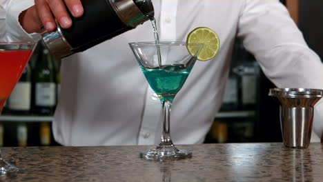 Barman-pouring-cocktail-into-glass-