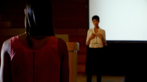 Young-businesswoman-asking-questions-to-Asian-female-speaker-during-seminar-in-auditorium-4k