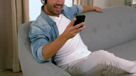 Smiling-man-with-headphones-using-smartphone