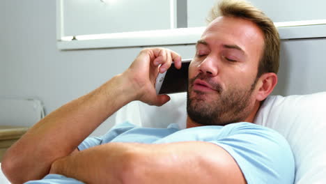 Man-calling-with-smartphone-and-lying-on-bed-