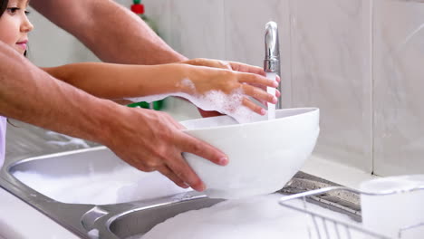 A-father-is-teaching-his-daughter-to-wash-the-dishes