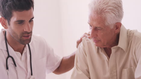 Male-doctor-consoling-senior-man