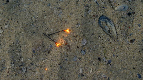 High-angle-view-of-sparklers-on-sand-at-beach-4k