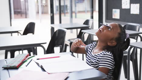 Ein-Junges-Afroamerikanisches-Mädchen-Sitzt-Am-Schreibtisch,-Bleistift-Auf-Der-Nase,-Kopierraum