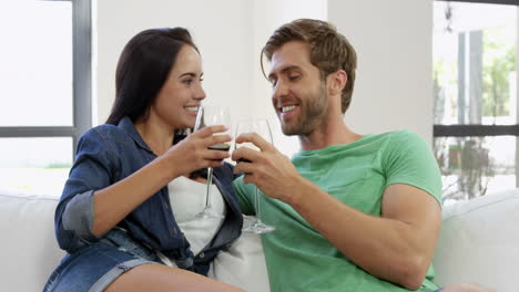 -Portrait-of-young-couple-sitting-on-sofa-with-a-glass-of-red-wine