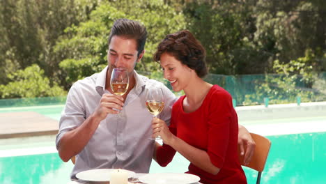 Smiling-couple-drinking-wine-poolside-