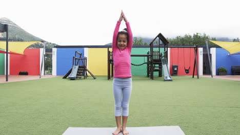 In-a-school-playground,-a-young-African-American-girl-practices-yoga