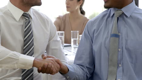 Businessman-handshaking-in-front-of-businesswoman-