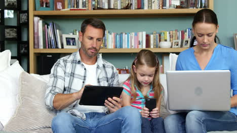 Cute-family-using-technologies-sitting-on-the-couch