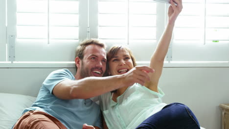 Cute-couple-lying-on-bed-taking-some-photos-with-smartphone