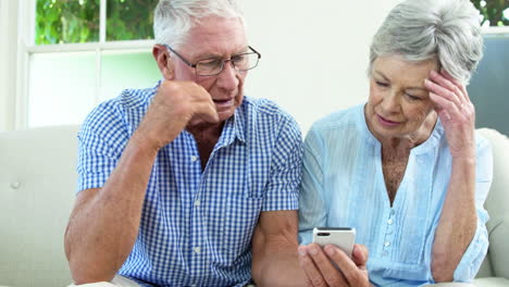 Worried-senior-couple-looking-at-smartphone
