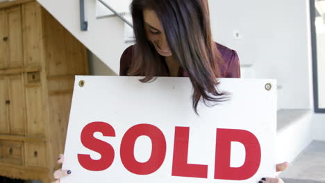 Woman-holding-billboard-which-is-written-SOLD