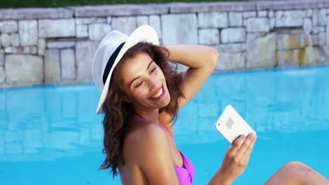 Smiling-woman-taking-photo-at-the-edge-of-pool