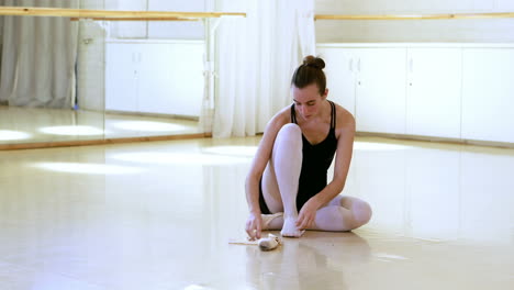 Portrait-of-ballerina-is-sitting-and-is-putting-on-her-dance-shoes