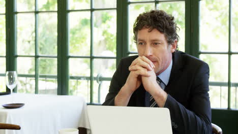 Close-up-of-thoughtful-businessman-sitting-in-front-of-laptop