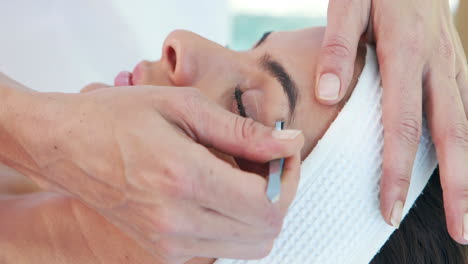 Woman-using-tweezers-on-patient-eyebrow