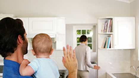 Father-holding-his-baby-and-saying-bye-to-his-wife-