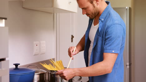 Hombre-Sonriente-Poniendo-Pasta-En-Una-Sartén