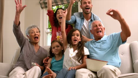 Multi-generation-family-on-the-sofa-cheering-while-watching-television