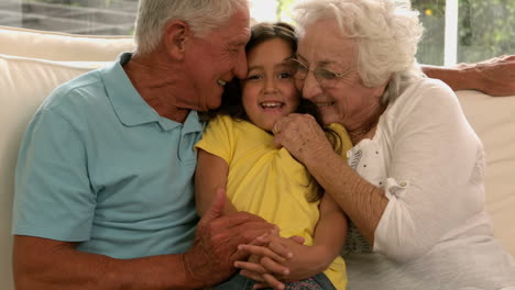 Grandparents-kissing-granddaughter-on-sofa