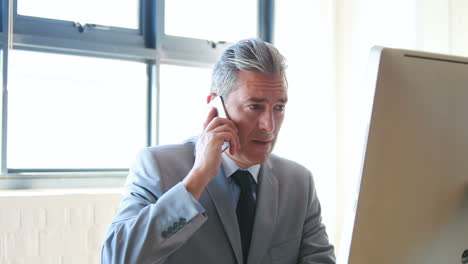 Businessman-using-his-computer-and-smartphone