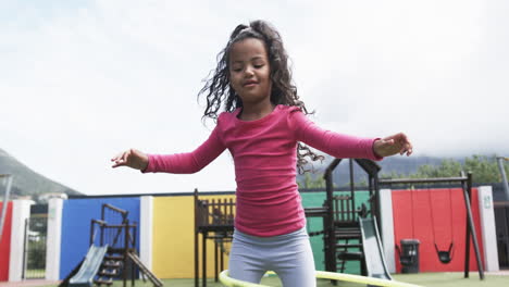 In-a-school-playground,-a-young-African-American-girl-is-hula-hooping