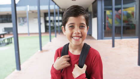 In-a-school-courtyard,-a-young-Caucasian-boy-smiles-brightly