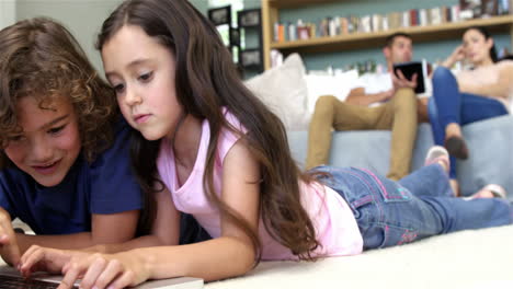 Zwei-Kinder-Benutzen-Den-Computer,-Während-Die-Eltern-Ein-Pad-Benutzen